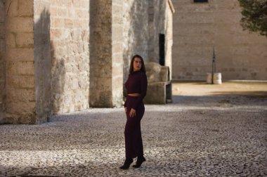 İspanya 'nın Seville kentindeki bir köyde, bir manastırın yanındaki kaldırım taşından bir sokakta poz veren zarif mor elbiseli güzel bir genç kadın. Kadın farklı ifadeler ve jestler yapıyor.