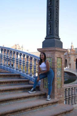 Genç, güzel, esmer Fas 'lı kadın beyaz bluz ve kot pantolon giymiş Seville' in İspanya meydanında. Kadınlar Endülüs, İspanya 'da tatilin tadını çıkarıyorlar. Seyahat ve turizm kavramı