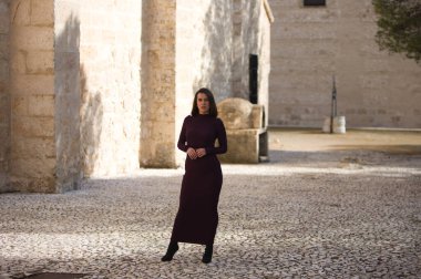 İspanya 'nın Seville kentindeki bir köyde, bir manastırın yanındaki kaldırım taşından bir sokakta poz veren zarif mor elbiseli güzel bir genç kadın. Kadın farklı ifadeler ve jestler yapıyor.