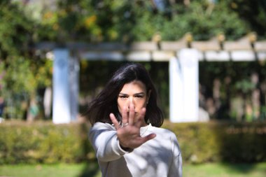 Genç, güzel, esmer Latin kadın elini kaldırdı ve dur dedi. Geçmek ya da devam etmek yok. Kötü muameleyi ve adaletsizliği durdurun. Yüzü odaklı ve eli odaksız