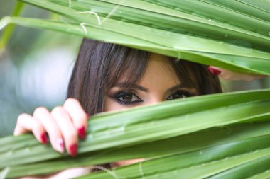 Güzel, genç esmer kadın elinde bir palmiye yaprağı tutuyor ve ona bakıyor. Kadın, İspanyol bir kadının büyük siyah gözleriyle çok anlamlı. Güzellik ve moda