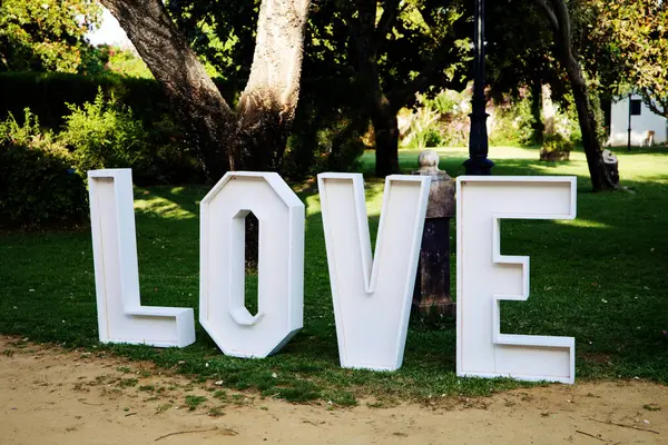 Bahçede beyaz ahşap aşk mektupları. Açık hava düğününün dekorasyonunda.