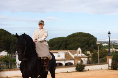 Endülüs, İspanya 'da siyah safkan bir İspanyol atına binen genç ve güzel bir kadın. Kadın tipik bir atlı kadın kostümü giyiyor. Ufukta mavi gökyüzü ve beyaz bulutlar