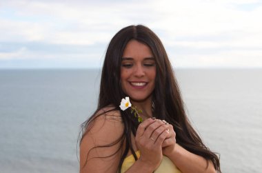 Elinde beyaz bir çiçek tutan genç, güzel esmer bir kadının portresi. Kız mutlu ve gülümsüyor. Arka planda gökyüzünün denizle buluştuğu ufuk.