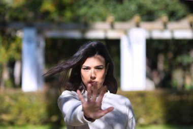 Genç, güzel, esmer Latin kadın elini kaldırdı ve dur dedi. Geçmek ya da devam etmek yok. Kötü muameleyi ve adaletsizliği durdurun. Yüzü odaklı ve eli odaksız