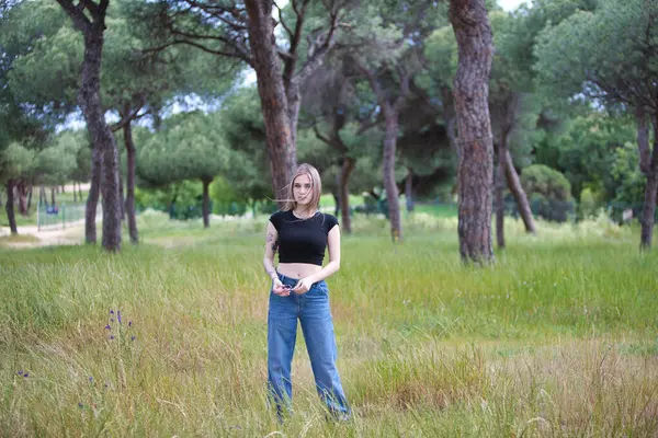 Genç ve güzel sarışın kadın, kot giyen, siyah gömlekli ağaçlar ve çiçekler arasında tarlada yürüyen. Kadın yalnızlığın ve ormanın bahar gününün tadını çıkarıyor.