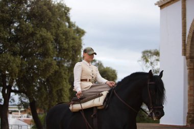 Endülüs, İspanya 'da siyah safkan bir İspanyol atına binen genç ve güzel bir kadın. Kadın tipik bir atlı kadın kostümü giyiyor. Ufukta mavi gökyüzü ve beyaz bulutlar