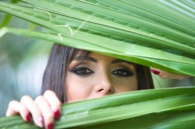 Güzel, genç esmer kadın elinde bir palmiye yaprağı tutuyor ve ona bakıyor. Kadın, İspanyol bir kadının büyük siyah gözleriyle çok anlamlı. Güzellik ve moda