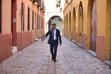 Genç, yakışıklı, koyu renk saçlı, takım elbiseli, kravatlı ve siyah dantelli ayakkabılı bir iş adamı telefonda konuşuyor ve sigara içiyor. Adam çok uluslu bir şirketin yöneticisi.