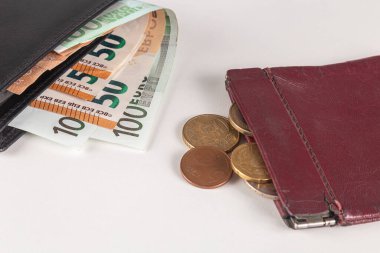 İçinde euro banknotları olan deri cüzdan, bozuk para dolu eski bir cüzdanın yanında.