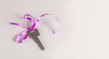 Beyaz bir yüzeyde pembe kurdeleli anahtar. Boşluğu kopyala.