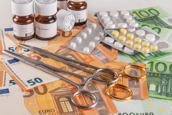 Medical instruments and medicines on a table covered with large quantity of euro banknotes on a light background close-up