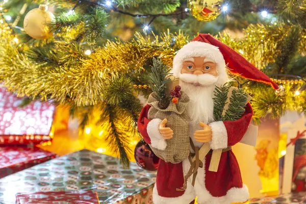 Noel Baba figürü ve Noel ağacının altında paketlenmiş hediyeler.