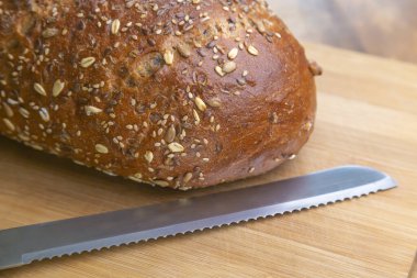 Taze pişmiş, çoklu tahıllı ekmek kesim tahtasının üzerinde bıçakla.