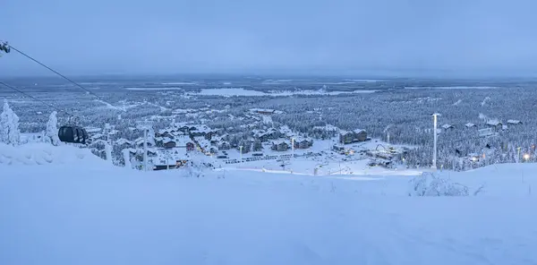 Finlandiya 'nın Levi köyünün kayak yamacından panoramik manzara, akşam ışıklarıyla kaplıdır..