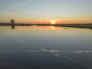 Gölün ve doğa alanının üzerinde gün batımı.