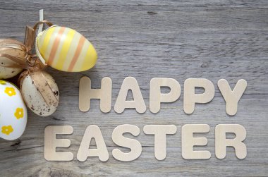 Süslü Paskalya yumurtalarıyla ahşap zemin üzerine Mutlu Paskalya metinleri