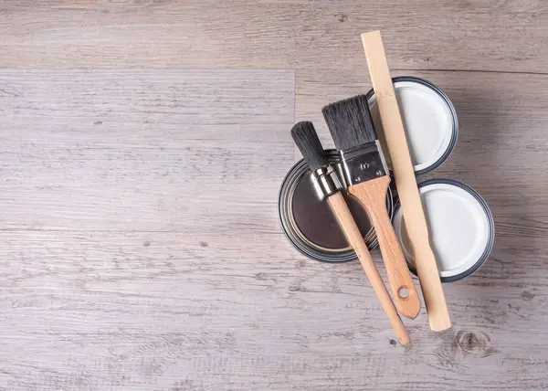 Evin yenilenmesi, boya kutuları ve fırçalar ahşap arka planda fotokopi alanı ile