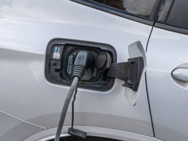 Halka açık bir şarj istasyonunda elektrik kablosu takılı.