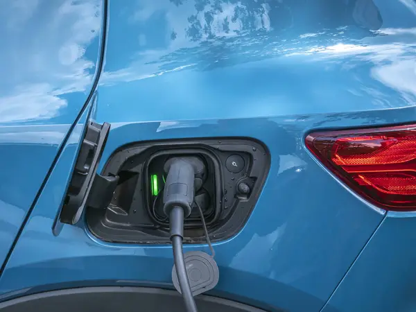 Halka açık şarj istasyonunda şarj etmek için elektrikli araca bağlı şarj kablosu..