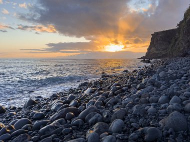 Okyanus kıyısında gün batımı dramatik gökyüzü ve ıslak kayalara yansıyan güneş. Madeira, Portekiz.