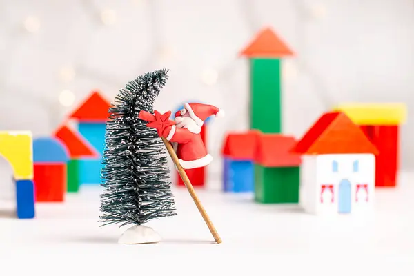 Plastikçi Noel Baba, Noel ağacına bir yıldızı ahşap bloklardan yapılmış bir köyün bulanık arka planına asmaya çalışır. Noel ve Yeni Yıl kavramı.