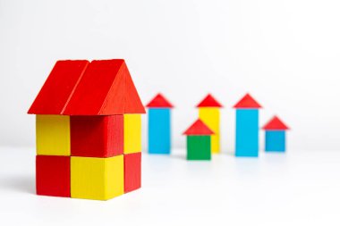 Arka plandaki büyük ev beyaz arka planda, ahşap renkli bloklardan yapılmış küçük evler.