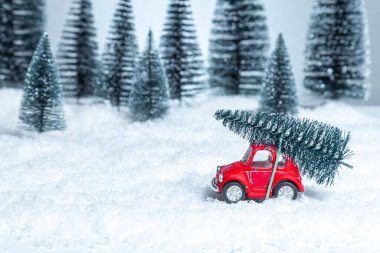 Çatıda Noel ağacı olan bir kış ormanında kırmızı oyuncak araba. Noel ve Yeni Yıl kavramı.