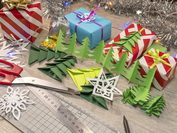 Kağıt çelenkler, Noel ağaçları, kar taneleri ve masaya sarılmış Noel hediyeleri. Noel ve Yeni Yıl kavramı.