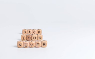 never look back! phrase on wooden blocks with black letters on white background clipart