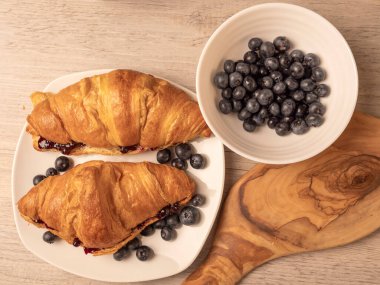 Reçelli kruvasan ve ahşap masada taze yaban mersini. Üst görünüm.