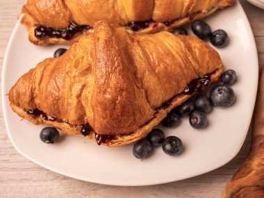 Reçelli kruvasan ve beyaz tabakta yaban mersini. Kapat. 