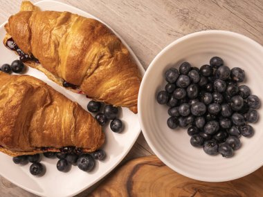 Beyaz tabakta yaban mersini ve kruvasan getir. Üst görünüm.