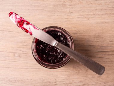 Bir kavanoz yaban mersini reçeli üzerinde bıçak. Üst görünüm.