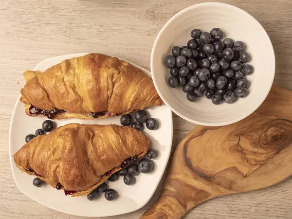 Reçelli kruvasan ve ahşap masada taze yaban mersini. Üst görünüm.
