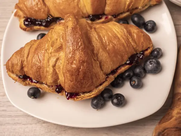 Reçelli kruvasan ve beyaz tabakta yaban mersini. Kapat. 