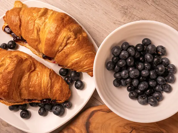 Beyaz tabakta yaban mersini ve kruvasan getir. Üst görünüm.