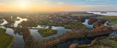 Günbatımında su yolları ve doğa ile çevrili güçlendirilmiş tarihi bir kasabanın havadan panoramik görüntüsü. Hollanda, Naarden..