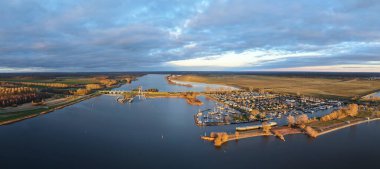 Yat limanında sakin bir gün batımı. Tekneleri ve yemyeşil suları suya yansıyor.