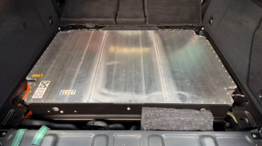 Görünür uyarı etiketleri, geri dönüşüm sembolleri ve metal kaplamalı elektrikli araba aküsü..