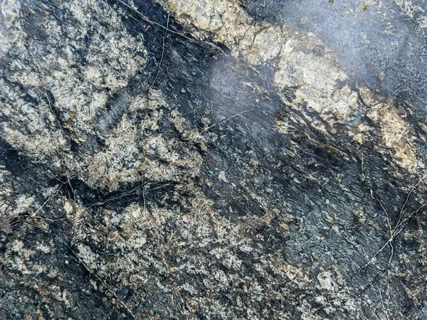 Kırık ve yosunlu doğal bir taş dokusu, pürüzlü ve yıpranmış detayları gösteriyor..