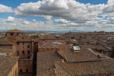 İtalya 'nın Siena kentinin manzarası, ortaçağ mimarisini gösteriyor. Terracotta çatıları ve tepeleri uzakta..