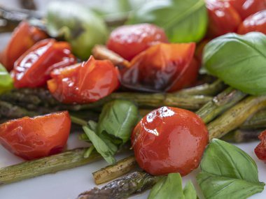 Beyaz tabakta kiraz domatesli, fesleğenli, hafif ve Akdeniz aromalı kuşkonmaz..