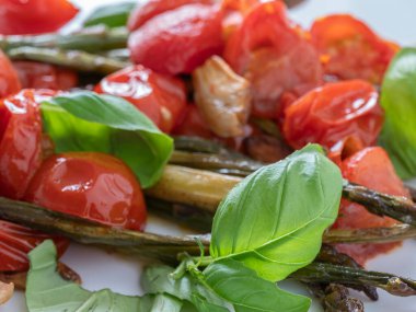 Lezzetli ızgara kuşkonmaz, olgun domates ve taze fesleğen yaprağı, sağlıklı beslenenler için mükemmel bir vejetaryen seçeneği..