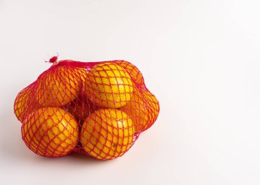 Kırmızı ağ çantasındaki parlak portakallar, beyaz arkaplanda izole edilmiş..