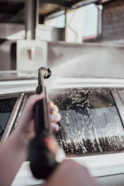 Arabasını yıkayan bir kadın. Arabasıyla ilgilenen genç bir kız..