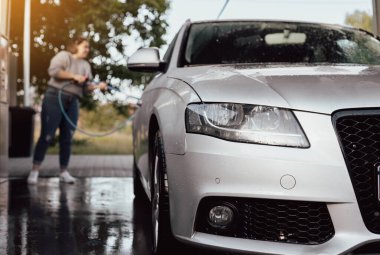 Arabasını yıkayan bir kadın. Arabasıyla ilgilenen genç bir kız..