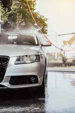 Arabasını yıkayan bir kadın. Arabasıyla ilgilenen genç bir kız..