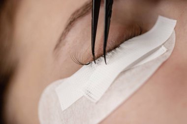 Kirpik uzatma prosedürü. Bir kız için kirpik uzatma yapan bir kadın.