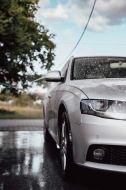 Arabasını yıkayan bir kadın. Arabasıyla ilgilenen genç bir kız..